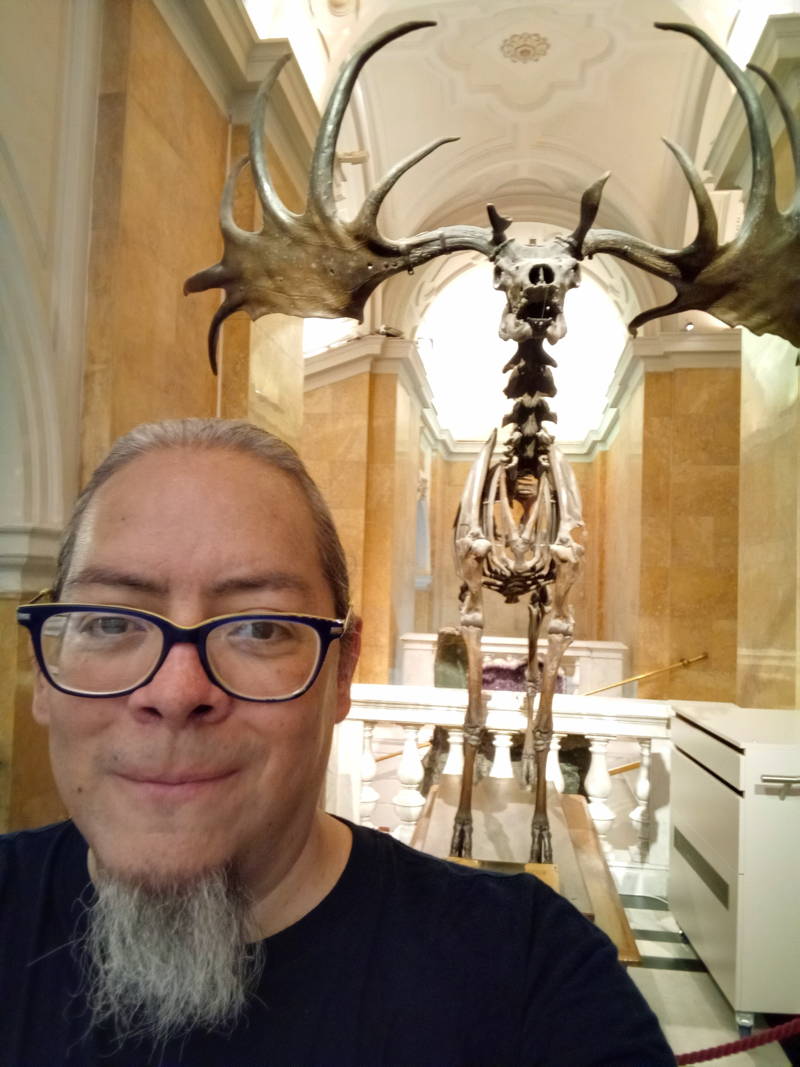 C D Suarez Pascal posing in a museum with a Megaloceros skeleton in the background