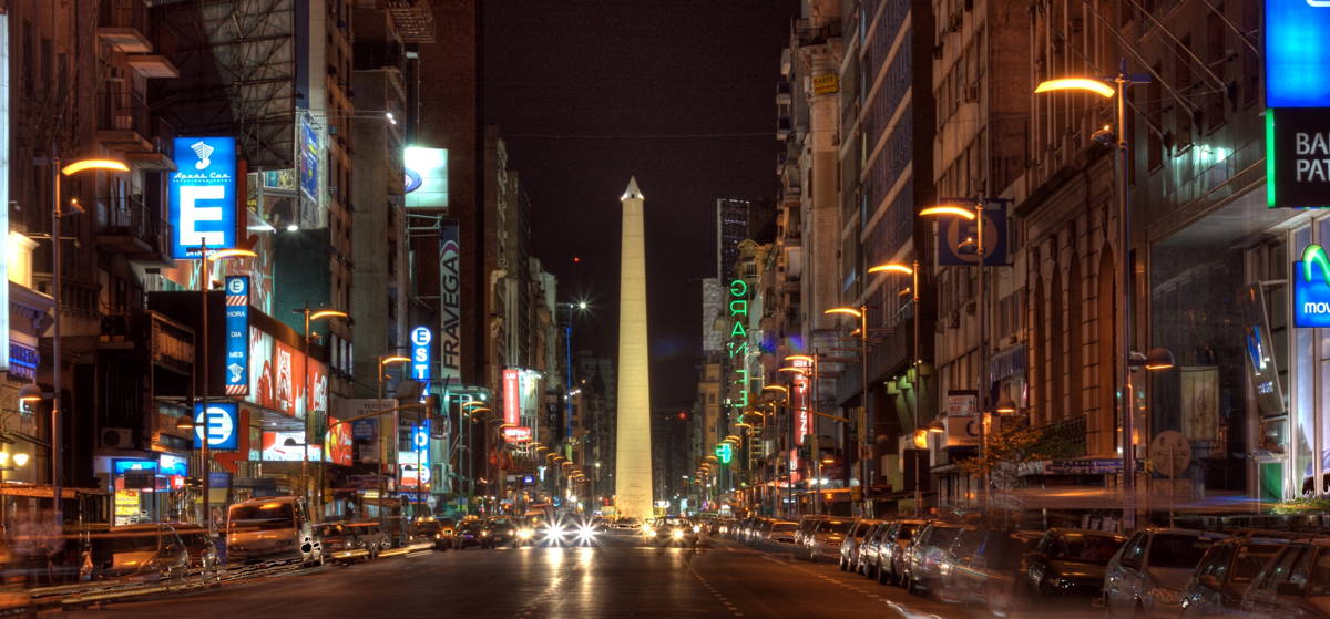 A picture of the Corrientes avenue at night with the obelisk in the background
